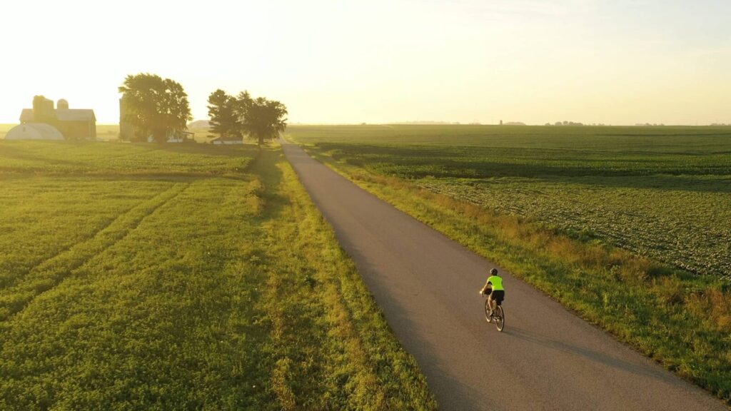Iowa Great Lakes Trail, cyclist riding along the trail with green farmland on either side