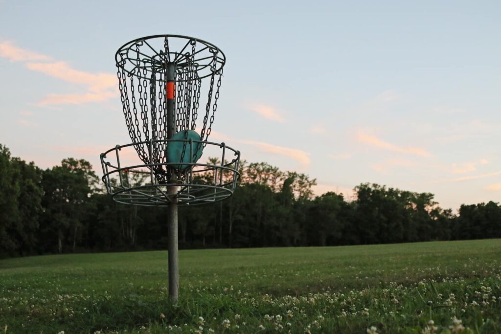 A disc golf basket in the green field on a sunny day at the Dickinson County Nature Center
